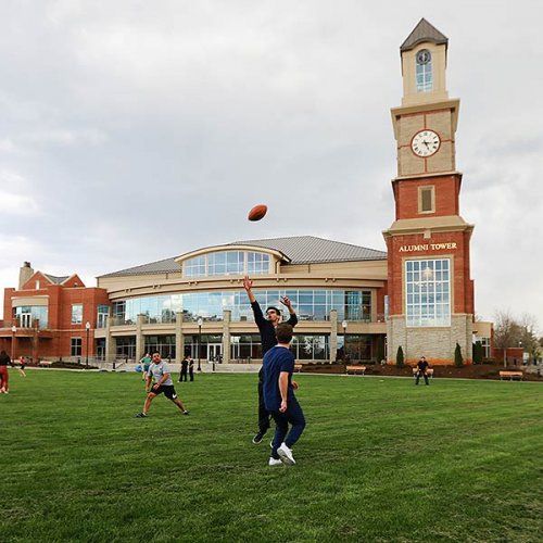 Students playing football on parade field in front of Student Center